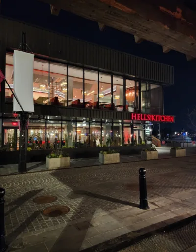 A restaurant is lit up at night in front of a building.