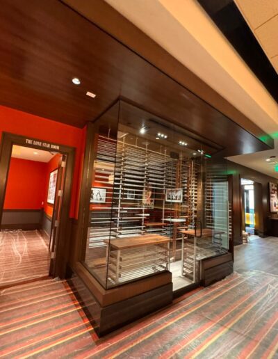 A glass-walled room with metal shelving inside, located in a hallway with wood-paneled walls and striped flooring; a sign reads "THE LINE STAR ROOM.