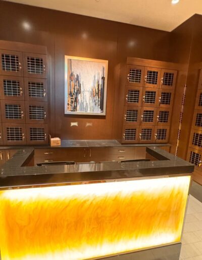 A reception desk with a glowing front panel is positioned in front of wood-paneled walls featuring multiple mailboxes and a cityscape painting.